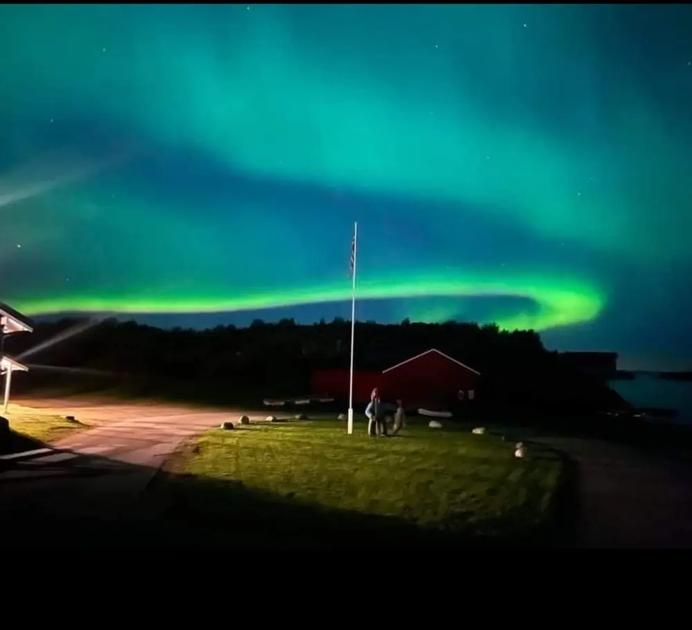 Grønt nordlys over campingplassens flaggstang om natten