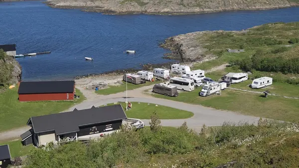 Luftfoto av vika med bobiler parkert ved det blå vannet