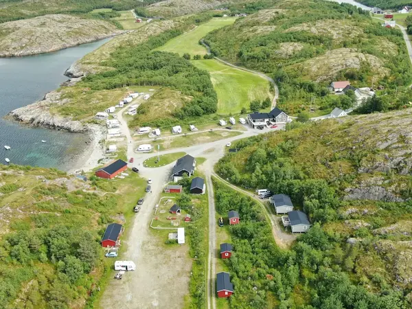 Dronefoto av hytterekka langs gruslageret ned mot sjøen