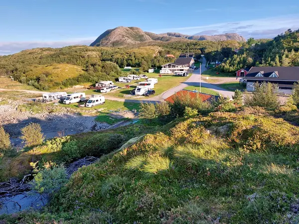 Vidt luftfoto av campingområdet omkranset av fjell og vann