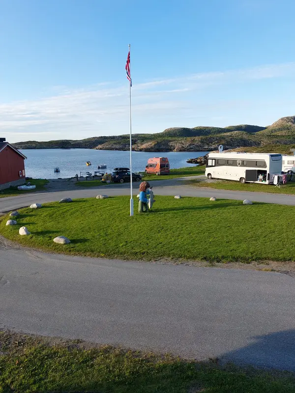 Campingplassens flaggstang en klar sommerdag, med vika i bakgrunnen