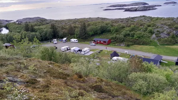 Luftfoto av åssiden med ei rød hytte blant campingplassene